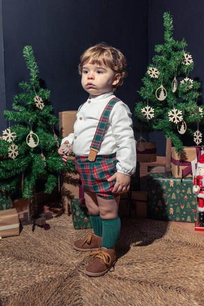 Child in festive outfit with Christmas trees and decorations in the background